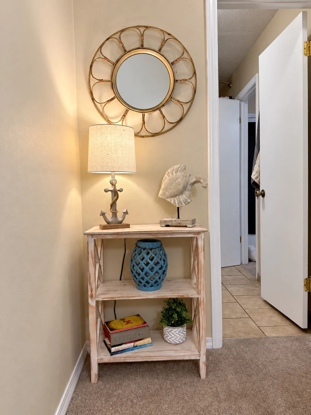 Coastal decor detail at Baker's Tide with round mirror, lamp, fish sculpture and blue accent stool