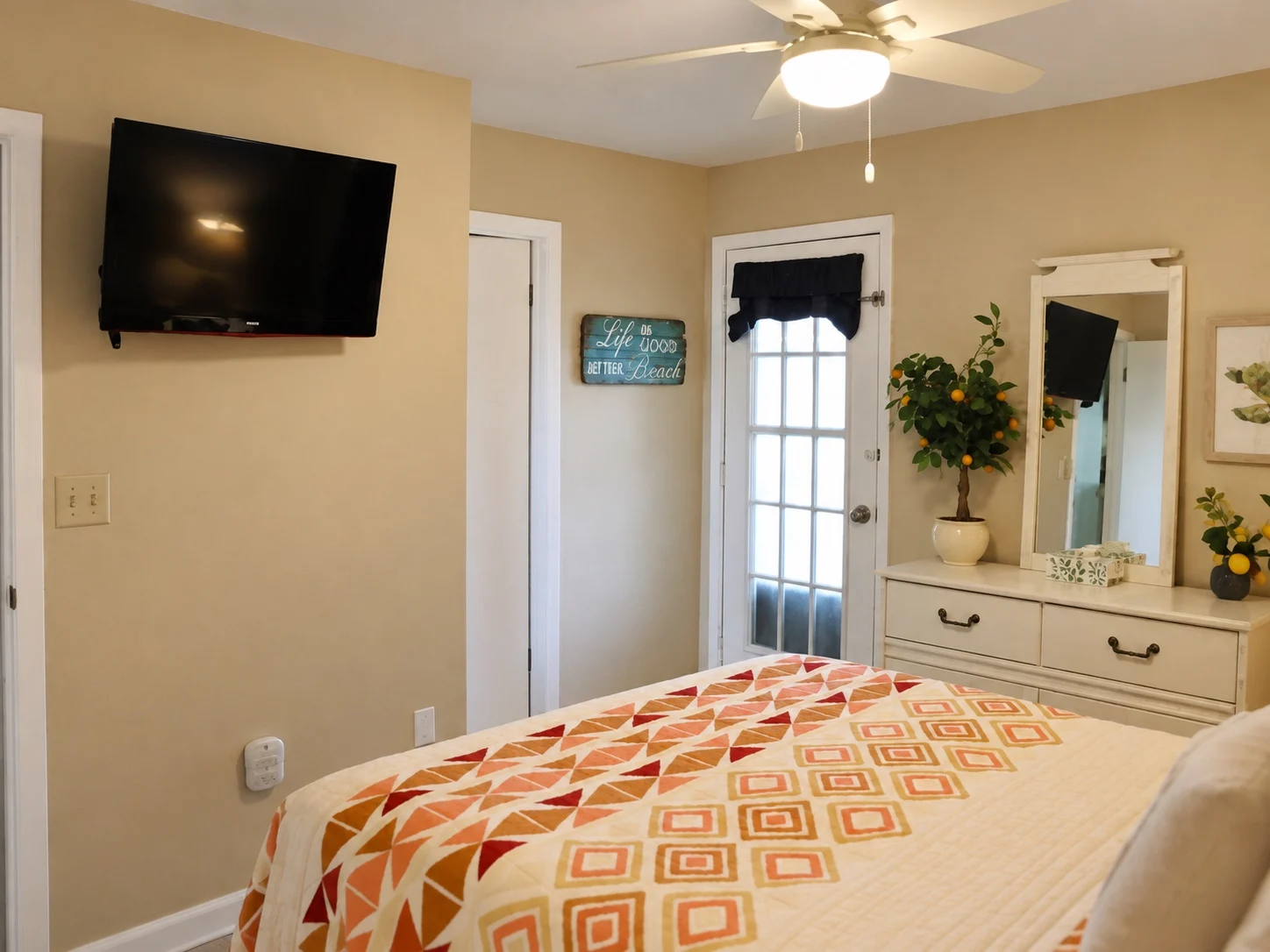 Alternate view of the coral coastal bedroom showing television, dresser and exterior door