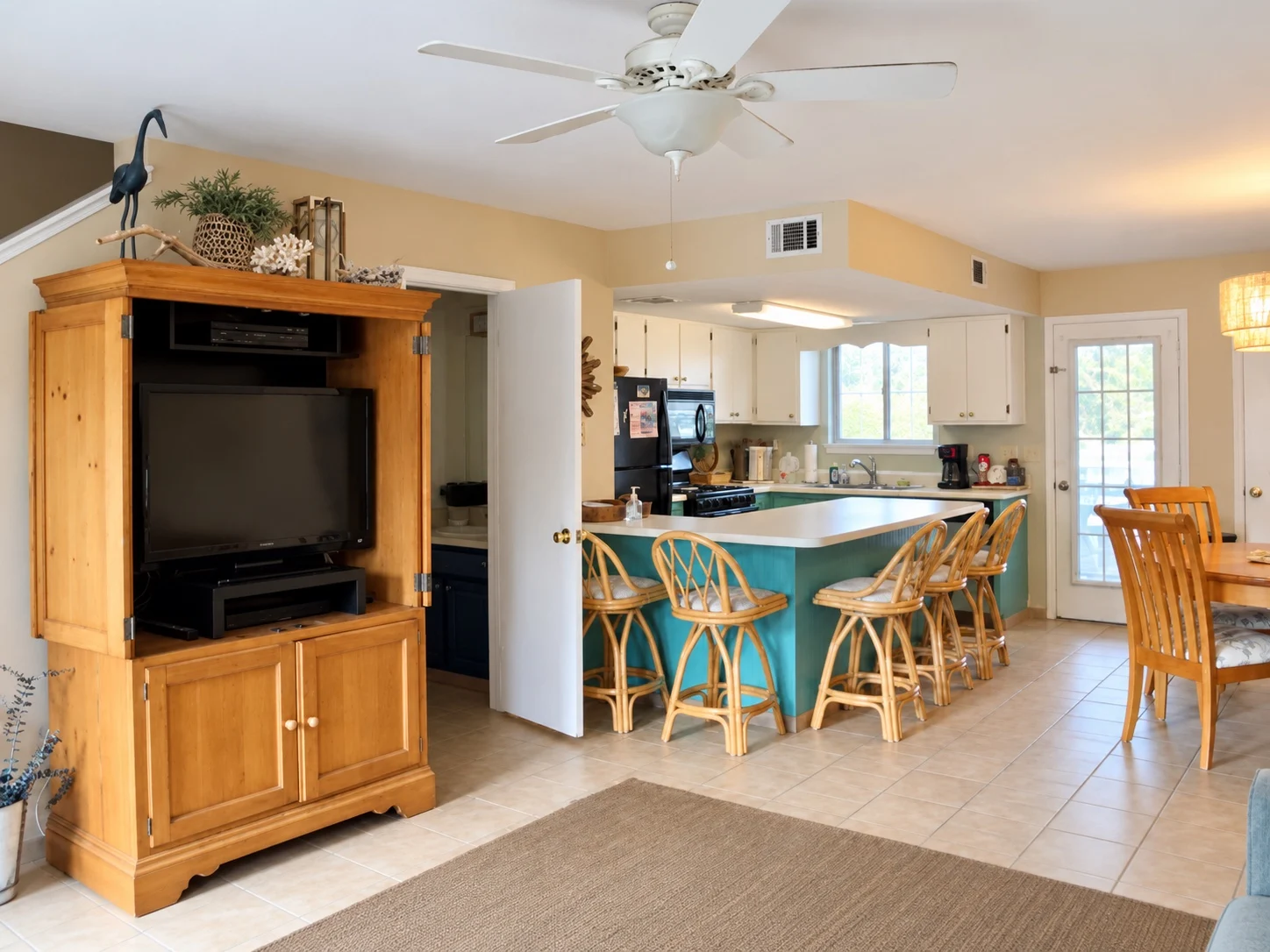 Wide view across the living area toward the turquoise and white kitchen at Baker's Tide