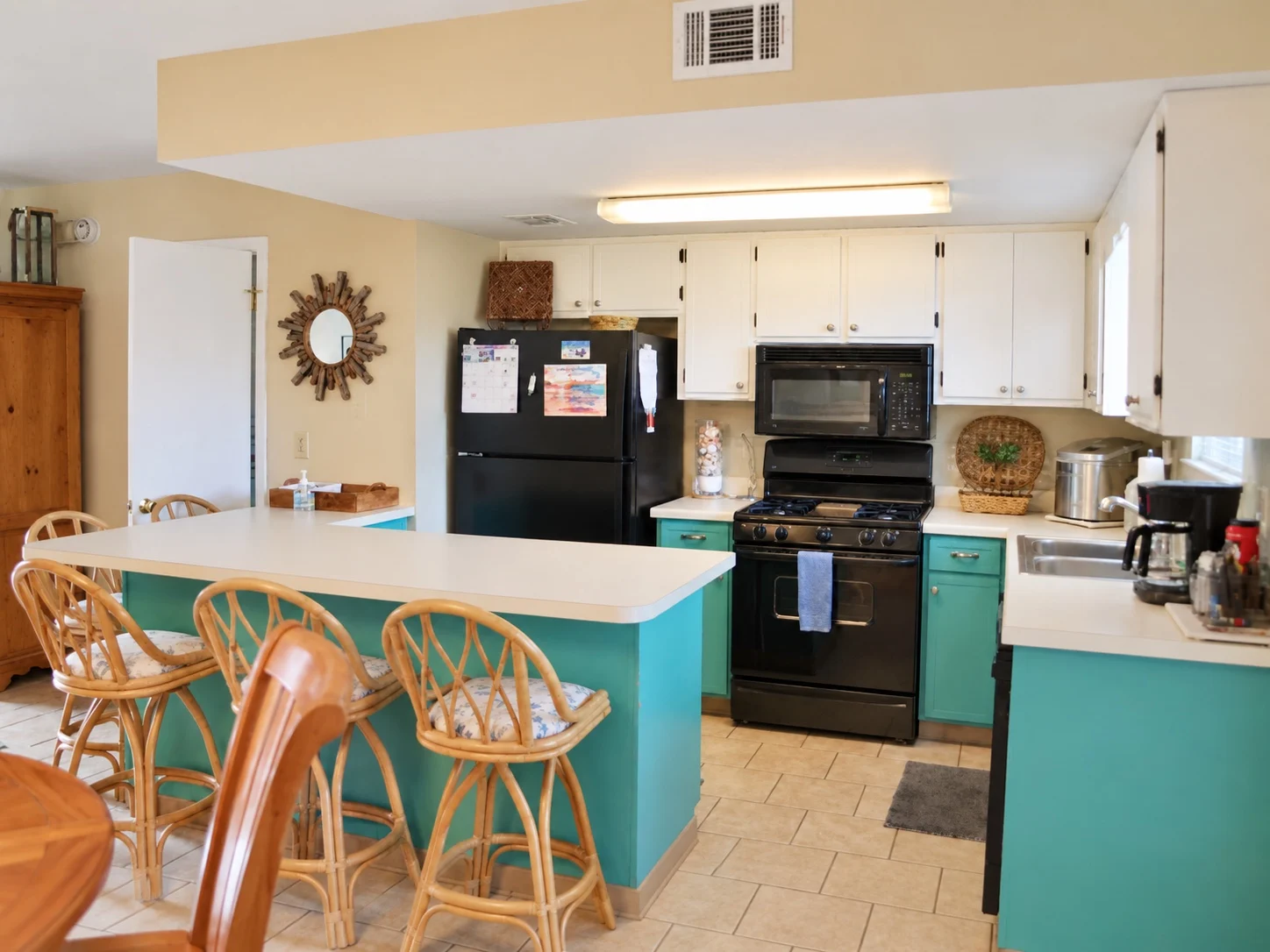 Current Baker's Tide kitchen with turquoise cabinets, white counters and breakfast bar seating